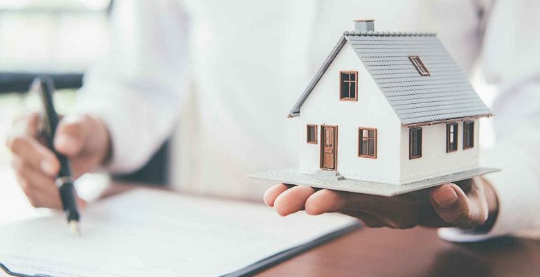 Una persona sostiene una vivienda en su mano